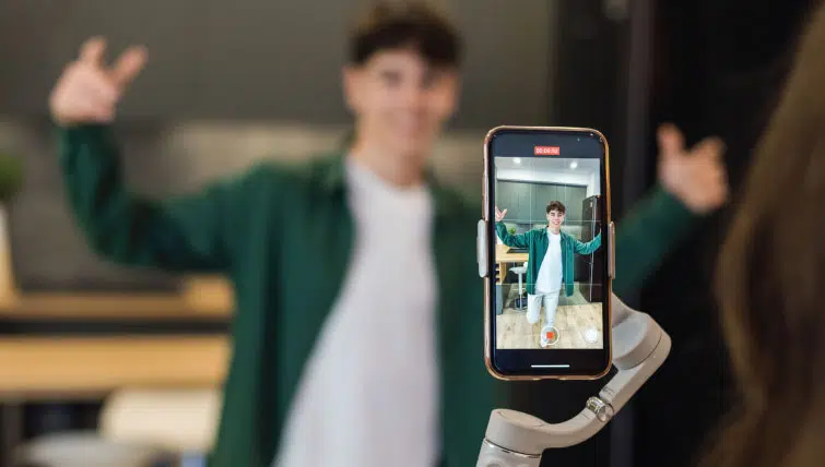A young male online influencer recording a video of himself with his phone.